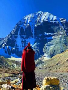 monk wearing red spiritual dress greetings towards mount kailash parvat by joining hands. 